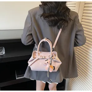 Detailansicht der rosa Ledertasche mit dekorativem Pferdeanhänger und Schultergurt