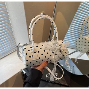 Detail of polka dot cylinder bag with lace bow and pearl chain pendant on a windowsill