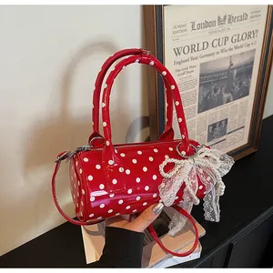 Detailed macro of red polka dot cylinder bag with lace bow and pearl charm