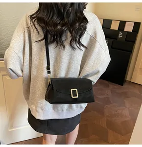 Classic black leather crossbody bag with gold buckle worn with casual autumn outfit