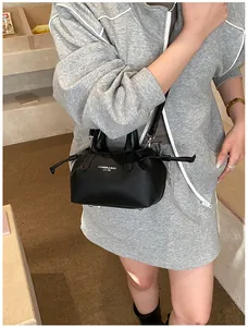 Detail of black pebbled leather tote bag with white fashion text and silver hardware