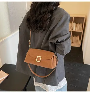 Detailed view of caramel suede pillow bag with gold clasp shown on model shoulder