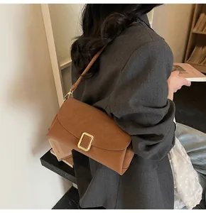 Detail of vintage brown leather crossbody bag with gold rectangular metal buckle