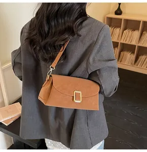 Close-up of a brown leather crossbody bag with gold metal buckle on a model in a suit