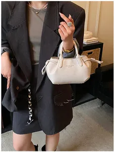 Close-up of litchi texture cream tote bag with side drawstring details on gray blazer