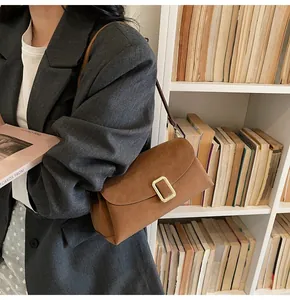 Close-up of retro brown suede crossbody bag with gold buckle on a model in library