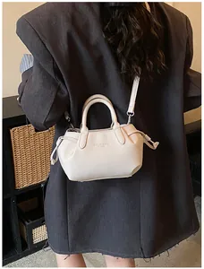 Detail of beige lychee grain leather handbag with embossed letters and drawstring