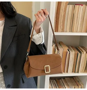 Close-up of the vintage brown leather shoulder bag with a gold buckle and matte texture