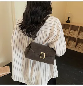 Detail of a dark brown matte leather pillow bag with gold clasp shown on a model