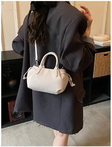 Chic cream litchi texture Boston bag featuring adjustable straps and knot details