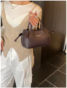 Detail of dark brown lychee leather tote bag featuring white text print and drawstring decoration