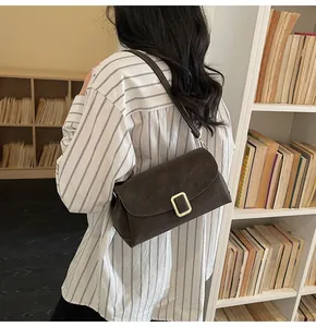 Detail of vintage brown shoulder bag with golden buckle shown in a bookstore setting