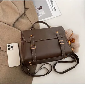 Λεπτομέρεια καφέ vintage σακιδίου με γούρι και iPhone 12 για σύγκριση μεγέθους