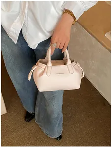 Close-up of litchi grain leather tote bag with drawstring bows and metal watch detail