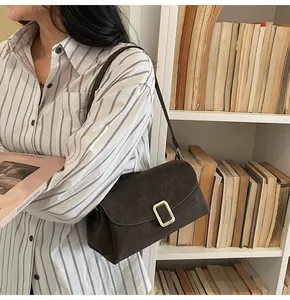 Close-up of a dark brown suede shoulder bag with a vintage gold buckle and slim strap