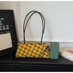 Detail of yellow and black plaid shoulder bag with metallic animal buckle and thin straps