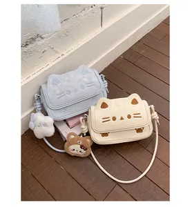 Detail of cute cat-shaped handbags in blue and cream with soft embroidery and plush charms