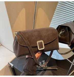 Detail view of the brown suede crossbody bag featuring a golden rectangular metal buckle