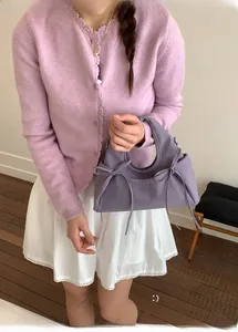 Detail of purple cloud handbag with bows styled on a shoulder bag for a trendy look