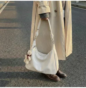 Close-up of ivory white hobo shoulder bag with a cute brown teddy bear keychain charm
