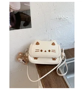 Detail of cute cat shaped crossbody bag in off-white with brown bear plush keychain charm