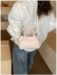 Detail of light pink pebbled leather tote bag with side drawstring and crossbody strap