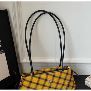 Detailed view of yellow and black checkered shoulder bag with silver metallic logo