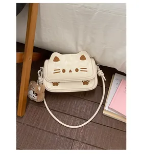 Detail of cream cartoon cat crossbody bag with embroidery and brown plush bear charm