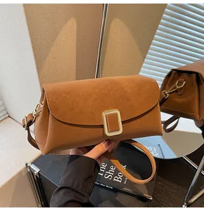 Close-up of brown faux leather crossbody bag with a square gold metallic clasp buckle