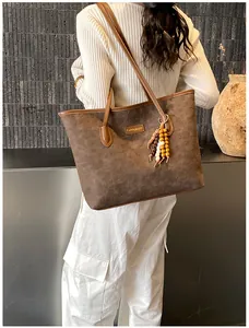 Detail of dark brown tote bag with embossed pattern and colorful wooden bead accessory