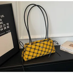 Close-up of yellow and black plaid shoulder bag with thin straps on a dark shelf
