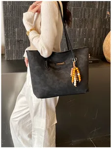 Detail of black tote bag with embossed logo texture and colorful wooden bead tassel charm