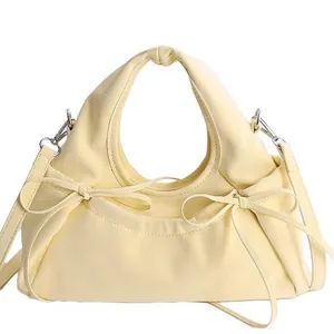 Pale yellow crescent bag with decorative bows and adjustable shoulder strap for women