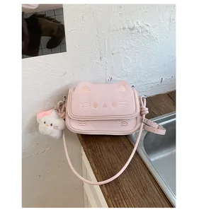 Close-up of pink cat-themed handbag with embroidered face and white plush kitty charm