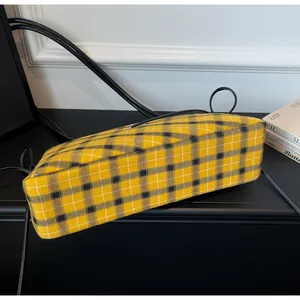 Close-up of yellow and black plaid canvas bag base and fine black leather straps