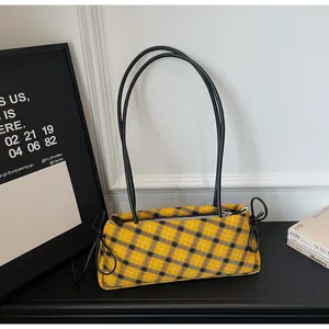 Detail shot of yellow and black checkered hobo bag with slim black shoulder straps