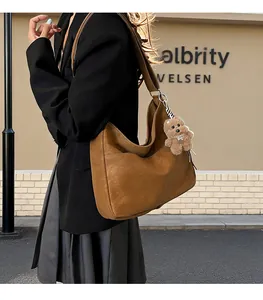 Vue détaillée latérale d'un sac cabas marron vintage avec un porte-clé ours en peluche
