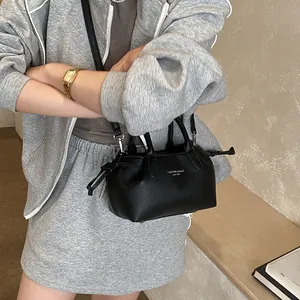 Minimalist black leather tote bag with shoulder strap worn by a model in casual style