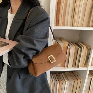Brown leather crossbody pillow bag with gold clasp shown in a professional office setting