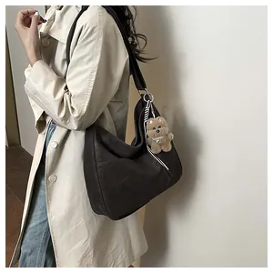 Détail du sac cabas en similicuir marron foncé avec large bandoulière et pendentif ours
