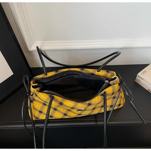 Detail view of yellow checkered hobo bag with leather handles and silver horse logo