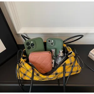 Macro view of plaid canvas bag showing spacious interior with phones and perfume