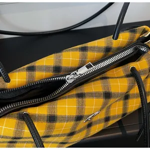 Close-up of silver metal zipper closure and plaid canvas texture on large tote bag