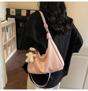 Detail of light pink moon hobo bag with knotted shoulder strap and plush bear charm