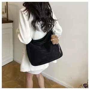 Vue arrière du sac hobo noir avec un charm ours en peluche porté par un modèle