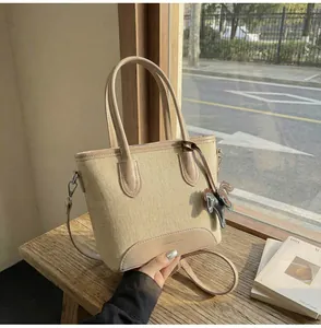 Detalle de bolso cubo de lona con ribetes de cuero, asa y colgante de caballo