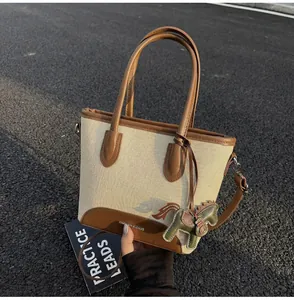 Detalle del bolso saco de lona con ribete de cuero marrón y colgante de caballo verde