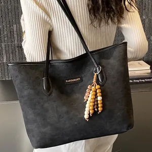 Minimalist black embossed suede tote bag with wooden bead charm and shoulder strap