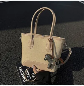 Detalle de bolso cubo de lona con ribete de cuero y colgante de caballo deco