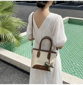 Detalle de bolso cubo de lona con ribete de cuero y amuleto de caballo junto a una piscina